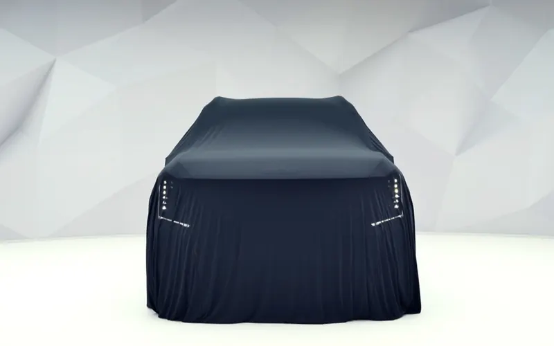 A car under a dark cover in a white room